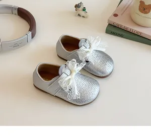 Detailed view of silver girls' shoes featuring intricate lace bow and velcro strap