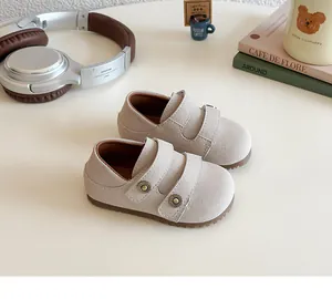 Dettaglio di mocassini beige per bambini con borchie retrò e chiusure a velcro