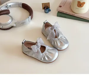 Detail of silver Mary Jane girl shoes with mesh bow and elastic collar on light table