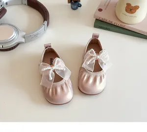 Top view of girls pink Mary Jane shoes with large lace bow and pearl bead decoration