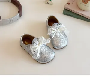 Detail of silver girls' dress shoes featuring woven texture and a large white lace bow