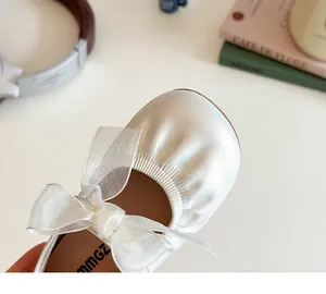 Close-up of cream white girls' Mary Jane flats with delicate mesh bow detail and round toe