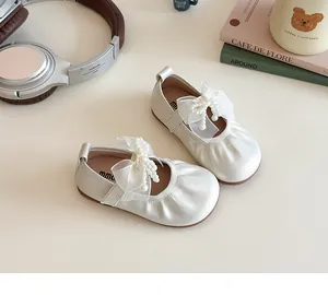 Close-up of white Mary Jane shoes with delicate tulle bows and decorative pearls