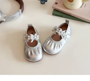 Détail de babies argentées pour filles avec nœud perlé et bande élastique sur fond crème