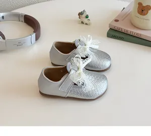 Detail view of silver toddler princess shoes featuring a delicate white lace bow and hook-and-loop strap