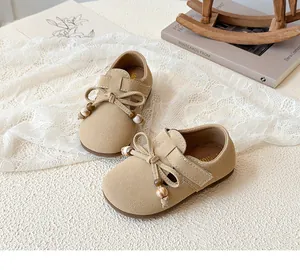 Detail view of beige girls' flat shoes with bowknot and beads on soft suede fabric