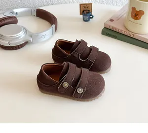 Dettaglio di scarpe casual in camoscio marrone scuro con chiusura a velcro e fibbie