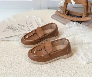 Detail von dunkelbraunen Mädchen-Loafern mit Metallschnalle und weichem Leder-Finish
