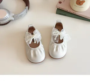 Detailed top view of cream girls' flats with pearl bow and organza on a soft background