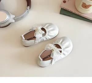 Detail of white Mary Jane shoes with pearl bow and velcro strap for girls