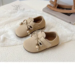 Detail of beige suede girl's princess shoes featuring bow tie with decorative pearls