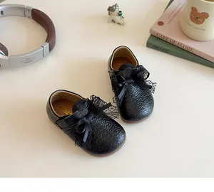 Detail of girl's black ballet flat with lace bow and woven texture in a cozy setting