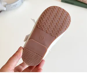 Close-up of flexible brown rubber sole with wavy anti-slip texture on white girls shoes