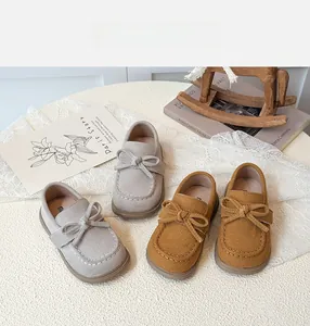 Close-up of children's suede bow loafers in grey and brown with decorative stitching