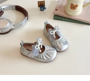 Close-up of silver girls' Mary Jane flats with mesh bow and faux pearl details