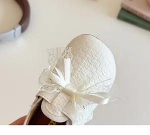 Close-up of white girls' princess shoes featuring woven texture and lace bow detail