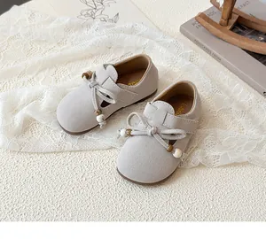 Detailed top view of girls' beige suede bow shoes with decorative beads on lace