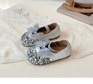 Close-up of silver sequined girls princess shoe with a grey mesh bow and rhinestone