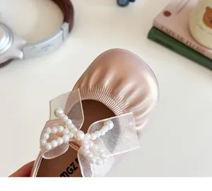 Detail of girls champagne pink pearl bow flats with metallic leather finish and mesh