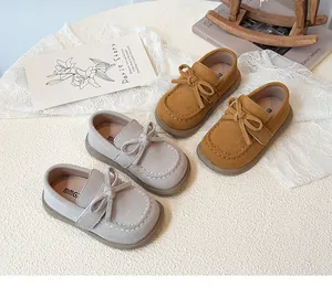 Detail view of suede kids' loafers in grey and brown with decorative bow and stitching