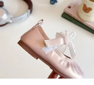 Detail of pink pearl leather girls shoes with bowknot and beaded cross decoration