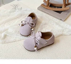 Close-up of girl's lavender suede flat with bow detail and velcro strap for a comfortable fit