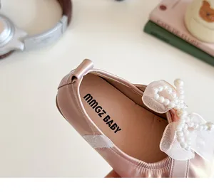 Close-up of pink girls' princess shoes featuring a delicate pearl beaded bow detail