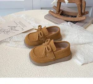 Detailed view of yellow suede girls loafers with handcrafted bow and rubber sole
