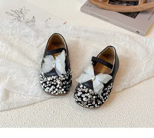 Close-up of black Mary Jane shoes with silver sequins, lace bow, and rhinestone detail