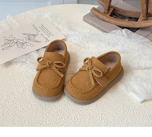 Detail of tan suede kids moccasins with bow accent and vintage prop background