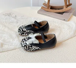 Detail of girls' black Mary Jane shoes with silver sequins and white mesh bow decoration