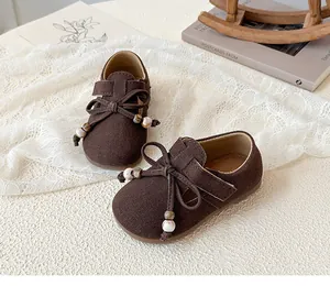 Detailed view of girls' brown faux suede shoes with bow accent and marble bead laces