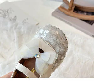 Close-up of girls' beige Mary Jane shoes with glitter toe and mesh bow detail