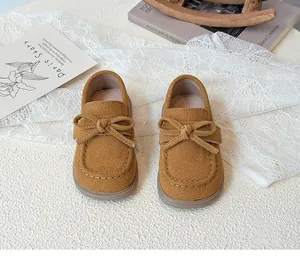 Detail of kids loafers with suede texture and bow decoration on a vintage scene