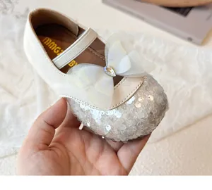 Detail of girls' cream Mary Jane shoes with sequins and a large mesh bow with rhinestones