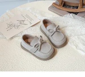 Close-up of children's beige bow loafers with contrast stitching and non-slip rubber soles