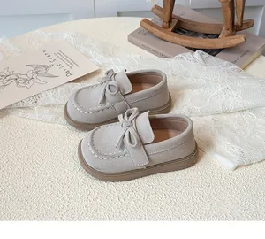 Close-up of light gray suede girls' shoes with bow detail and textured rubber sole