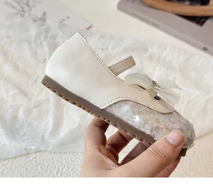 Close-up of beige girl's princess shoe featuring sequins, mesh flowers and gemstone detail
