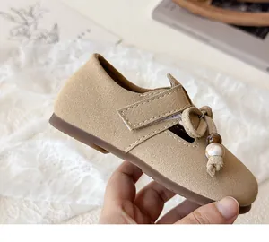 Detail of girl's khaki suede Mary Jane shoe with marble beads and braided knot decor