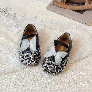 Girls black Mary Jane shoes with silver sequins and white organza bow on lace background