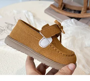 Detail of child's brown suede shoe featuring velcro strap and 3D bow accent