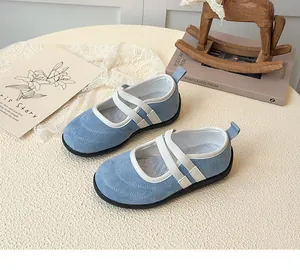 Gros plan de Mary Janes en daim bleu clair avec brides blanches sur une table beige