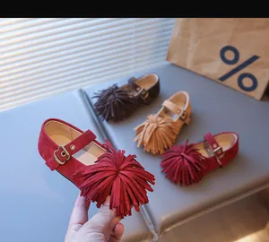Détail de chaussures en daim pour filles avec grand pompon et boucle en métal vintage