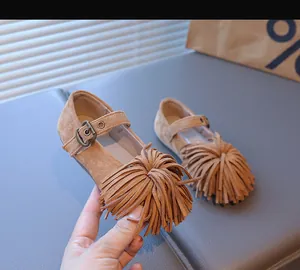 Détail de chaussure Mary Jane pour enfant en daim fauve avec pompons et boucle en métal