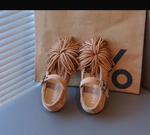 Gros plan de chaussures enfant en daim marron avec franges et boucle métallique
