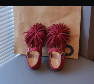 Détail de chaussures de princesse rouges en daim pour filles avec glands et bande auto-agrippante