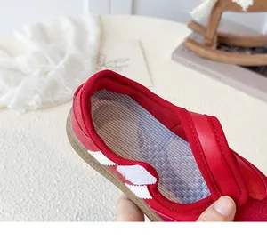 Gedetailleerde close-up van retro rode leren kindersneakers met witte strepen en gummizool