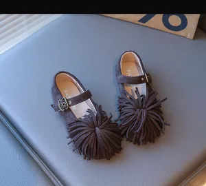 Détail de chaussures princesse en daim marron pour enfants avec franges et boucle métal