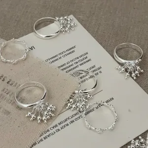 Detailed view of silver fireworks rings with beaded tassels and wavy textured bands