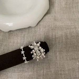 Detailed view of silver flower rings and cluster bead ring on a black jewelry stand